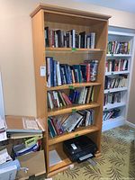 Full front view of wooden bookshelf with 5 shelves holding books and a printer at the bottom shelf, showing size and condition.