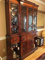 Full front view of entire breakfront cabinet showing upper glass doors, lower drawers, and open left cabinet door