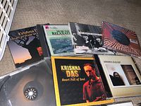 Close-up photo showing Krishna Das CD albums and other CDs on carpeted floor