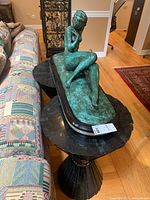 Front three-quarter view of patinated bronze figure on marble-acrylic base