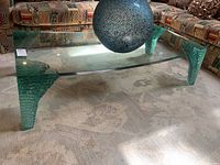 Three-quarter view showing curved glass top and layered glass legs