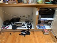 Wide view of cabinet interior showing multiple audio devices, headphones, cables