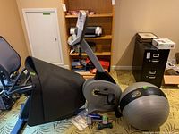 Full side view of Vision R20 recumbent exercise bike showing seat, backrest, pedals, and digital console, with balance ball and small hand weights on floor nearby