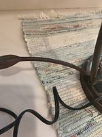 Close-up of mosaic tile base with dragonfly detail and dark bronze metal stem, showing loose connection points.