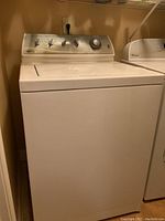 Front view of the white Maytag top-loading washing machine showing full exterior and control knobs.