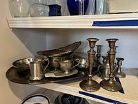 Shelf display of silver plate and sterling silver items including pierced basket and weighted candlesticks