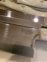 Close-up of Cutco knives with white handles showing 'Cutco Olean NY' marking