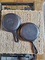 Bottom view of two cast iron pans showing branding and size markings