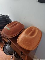 Two terra cotta clay bakers stacked on shelf with visible embossed floral patterns