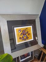 Angled view of framed Norval Morriseau art print showing textured silver frame and part of the print.