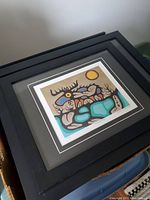 Framed Norval Morrisseau print seen from a distance in black frame with matting