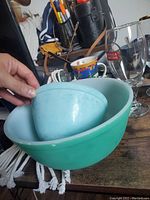 Photo of three nested Pyrex bowls in turquoise and aqua colors showing scratches and signs of wear.