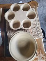 Top view of stoneware egg poacher insert with six round compartments and round cake pan underneath.