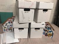 Four white comic book storage boxes labeled #1 to #4 stacked and arranged on a flat surface, with two Marvel-themed file holders on each side
