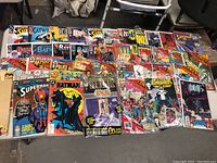 Table top view showing three rows of vintage comic books in poly bags and collector packs