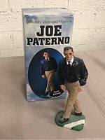 Figurine displayed alongside the original box, showing front and side view of the figurine and box.