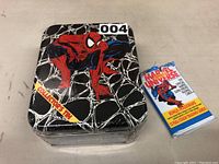 Front view of shrink-wrapped tin and sealed card pack