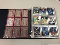 Binder opened showing fronts and backs of baseball sports cards in plastic sleeves