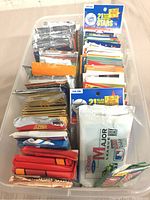 Top-down view showing large quantity of assorted sealed and loose sports card packs and individual cards in a large plastic container