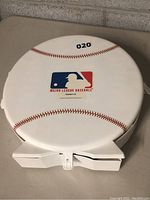 Photo of closed white round collector case featuring MLB logo with red stitching resembling a baseball.