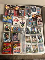 Overview of mixed vintage baseball sports card lot including unopened packs, boxes and loose cards in protective sheets