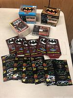 Photo of vintage Batman collector card boxes, loose cards in clear case, and multiple sealed card packs from Topps and McDonald's.