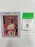 Card photo showing Allen Iverson smiling in Philadelphia 76ers hat holding a jersey, inside a plastic protecting case with 'ROOKIE CARD' printed at top.