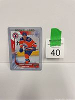 Connor McDavid rookie card in protective sleeve next to a maxsold lot number label.