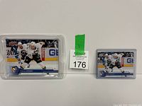 Two Sidney Crosby hockey cards in protective cases placed side by side with auction lot number between them.