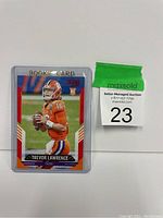 Photo of 2020 Score Rookie Card of Trevor Lawrence in LSU football uniform, card in rigid plastic case with auction label '23'