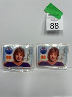 Two Wayne Gretzky Edmonton Oilers patches side by side, each showing his image, number 99, Oilers logo, and printed autograph. One patch has a visible pen mark.