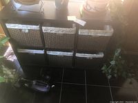 Front view of the dark wood basket organizer with six woven baskets placed in two rows of three.