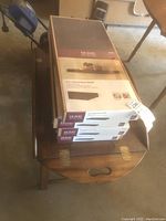 Photo of three boxed 24-inch decorative shelves stacked on a wooden table, with the label visible showing Home Decorators Collection brand and product information.