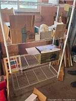 Photo of white metal wire storage shelf with three tiers and items placed on shelves, showing shelving structure and storage capacity.
