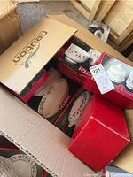 Box containing multiple original boxed pieces of holly Christmas china with visible holly pattern on boxes