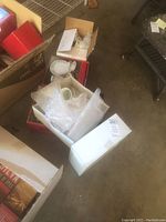Boxes containing bubble wrapped Christmas-themed mugs and china pieces, partially unpacked showing holly decorated white ceramic pieces