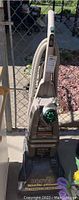 Front view of Hoover Steam Vac standing upright showing handle, flexible hose, and attached power cord.