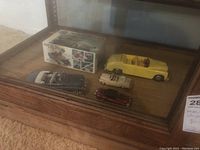 Display case showing five diecast model cars including yellow convertible and box in background.