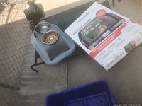 Photo of outdoor pet bed with attached food and water bowls alongside the Petmate wire pet barrier box.