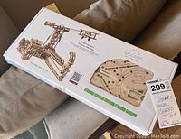 Long rectangular box with UGears branded mechanical model inside, showing laser-cut wooden boards through transparent window, sealed and new.