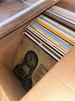 Photo of box filled with vintage vinyl LP covers showing classical music themed artwork and titles.
