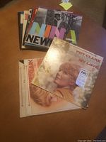 Photo of multiple vintage LP records including Pet Clark's 'My Love' and Nina Simone's 'Nina Simone at Newport' with visible album covers.