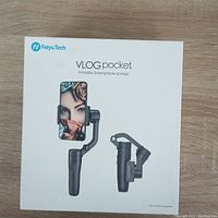 FeiyuTech VLOG Pocket gimbal in original box with front image showing phone mounted on gimbal and folded configuration.