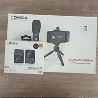 Comica Boom X-D and CVM-WS50(H) boxes showing product images and branding on wooden surface.