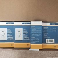 Front and side views of multiple boxes labeled 4.8A USB C Charger 15A Tamper Resistant Receptacle showing product details and packaging.
