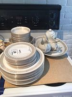 Stacks of dinner plates and dessert plates with bowls behind