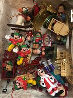 Top-down view showing multiple Disney Mickey Mouse Christmas themed miniature figurines including characters on bicycles, waving Mickeys, and a Santa Mickey figurine, along with other miniature holiday figurines and decorations.