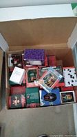 Open box showing multiple boxed Christmas ornaments and some loose ornaments inside.