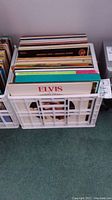 White plastic crate holding multiple LP vinyl records, including an Elvis Presley album visible in front.
