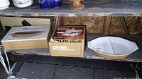 Vintage Pyrex items including two sets in original packaging on a surface and one oval divided serving dish outside packaging.